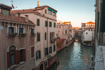 A serene view of a canal in Venice, Italy, with no gondolas or boats in sight. The predominant color of the buildings and the atmosphere are unspecified.