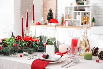 Festive table setting with Christmas decorations and burning candles in kitchen