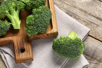 Board with fresh broccoli cabbages on wooden background - obrazy, fototapety, plakaty