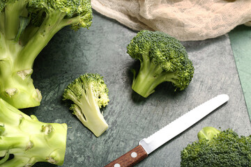 Board with fresh broccoli cabbages on green background, closeup