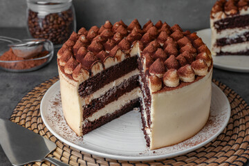 Delicious tiramisu cake with cocoa powder on table