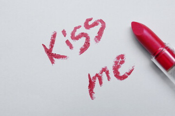 Red lipstick and phrase Kiss Me written on white background, top view
