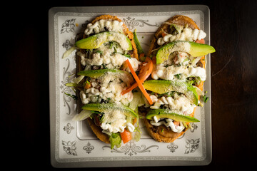Masa topped with refried beans, cheese and vegetables