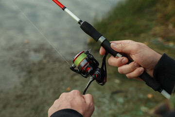 Fisherman with rod fishing at riverside, closeup