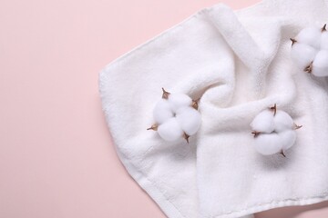 Fluffy cotton flowers and white terry towel on beige background, top view. Space for text