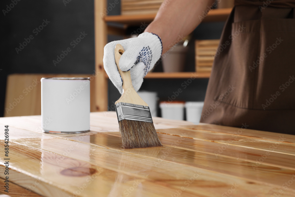 Canvas Prints Man varnishing wooden surface with brush indoors, closeup