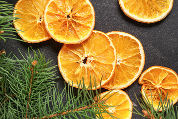 Dried orange slices and fir branches on black background