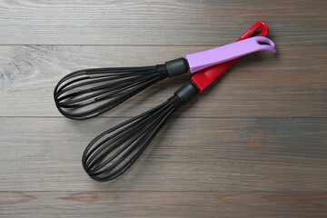 Two whisks on wooden table, top view. Kitchen tool