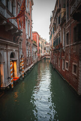 Explore the charm of Venice, Italy with this serene image capturing a narrow canal. The tranquil beauty of the architecture and water creates a picturesque scene.