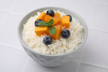 Bowl of delicious rice porridge with blueberries and pumpkin on white table, closeup