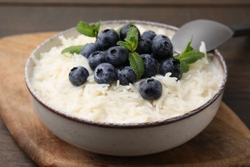 Bowl of delicious rice porridge with blueberries and mint served on table, closeup