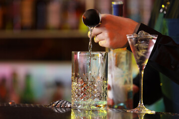 Bartender making fresh alcoholic cocktail at bar counter, closeup