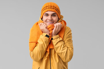 Young man in yellow stylish jacket and scarf on grey background