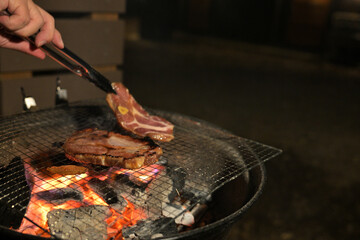 A glowing camp fire providing comfortable lights and barbecue grill pit with glowing and flaming of fire with hot charcoal briquettes with night time outdoor background