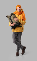 Naklejka premium Young man in yellow stylish jacket and scarf with bag on grey background