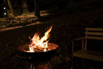 A glowing camp fire providing comfortable lights and barbecue grill pit with glowing and flaming of...