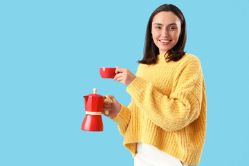 Pretty young woman with geyser coffee maker and cup of espresso on blue background