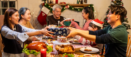 Asian lovely family exchanging presents during Christmas party at home.
