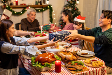 Asian lovely family exchanging presents during Christmas party at home.