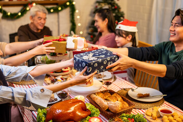 Asian lovely family exchanging presents during Christmas party at home.