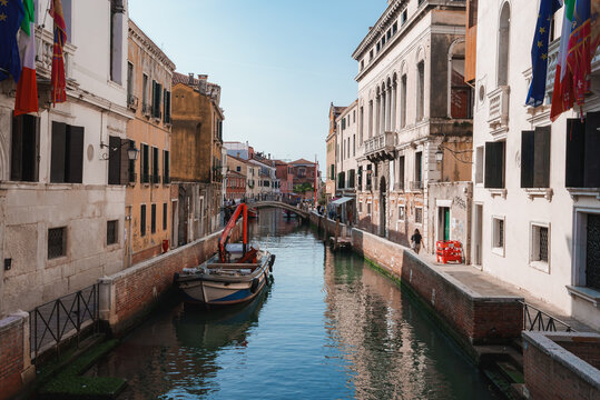 Scenic narrow canal in Venice, Italy with traditional architecture and boats. Serene waterway with no landmarks visible. Ideal for travel, tourism, and vacation concepts. © ingusk
