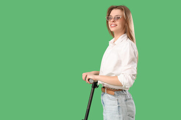 Young woman with electric scooter on green background
