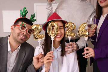 Happy young colleagues with figure 2024 celebrating New Year at corporate party in office, closeup