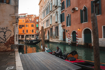 A peaceful gondola rests on a dock in Venice, Italy, surrounded by calm waters and charming...