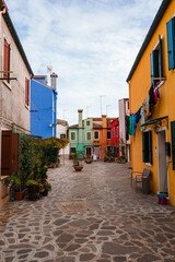 Fototapeta na wymiar Explore the charming and picturesque streets of Burano, Italy. Vibrant, colorful buildings line the narrow cobblestone street, capturing the essence of Venetian charm and local culture.