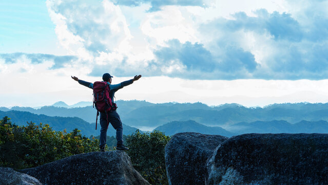 Asian Male Hiker cheering elated and blissful with arms raised in the sky after hiking. Mueang haeng camping ground, Chiang mai, Thailand.