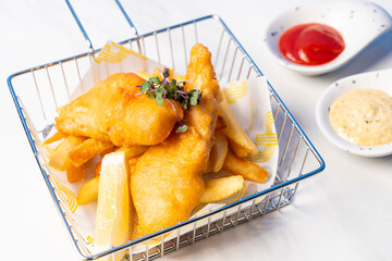 fish and chips in basket with sauce