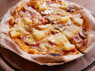 pizza with pineapple, mushrooms and sausage on a table, close up