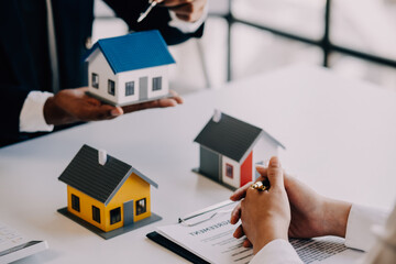 A couple is approaching a housing project to buy, and they are discussing details and advice with a salesperson in a housing project. Real estate trading ideas with couples.