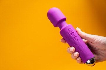 Woman holding purple vibrator on orange background. Copy space. 