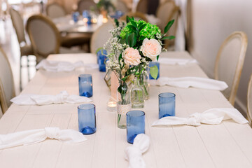 A pretty dining table set up for a party with a simple flower arrangement and blue vases. 