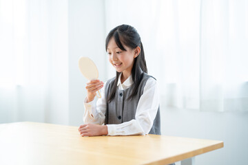 手鏡を持ち歯をチェックする日本人の女の子 - obrazy, fototapety, plakaty