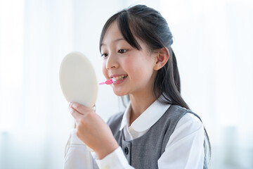 手鏡を持ち歯磨きをする日本人の女の子