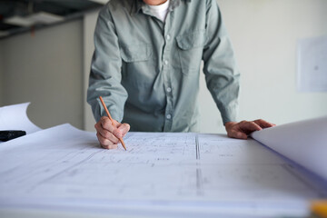 Architect correcting building blueprint on table
