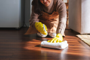 Closeup image of a woman wearing protective glove, wiping and cleaning the floor