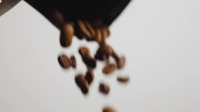 Coffee beans pouring out of a bag in slow ecu.