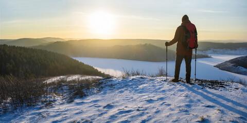 man hiker on top of a hill in winter at sunset. concept of discovery, exploration, hiking,...