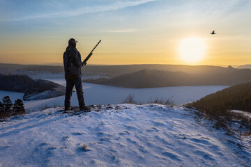 Hunter hunting on the bird, on black grouse in winter season. Winter hunt at sunrise or sunset.