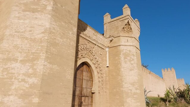 Stunning citadel towers on side of wooden keyhole gate entrance in Chellah Rabat Morocco