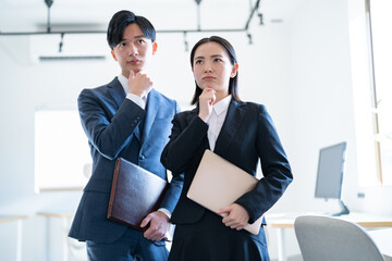 オフィスで考える若手のビジネスマン2人