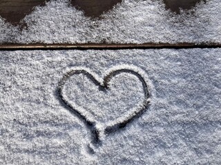 Ein Herz in den Schnee gemalt auf einer Bank in der Natur im Winter
