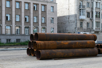 There are large rusty iron pipes on the road in the city.
