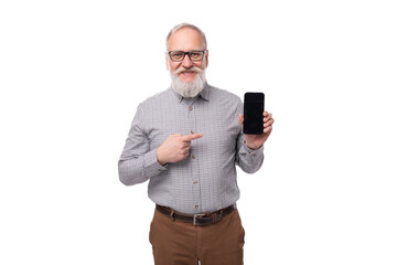 modern smart gray-haired mature businessman with a beard and mustache in a shirt and trousers holds a smartphone screen forward
