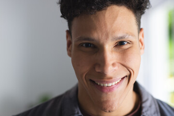 Portrait of happy biracial man in living room at home, copy space