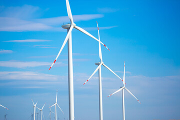 Fleet of power generators in motion. The blades of the wind farm rotate against the sky. The concept of extracting electricity from renewable sources. Wind turbine to generate electricity.