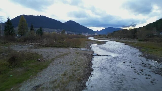 fast low flying aerial skimming the river before revealing the town of Campulung Moldovenesc in Romania